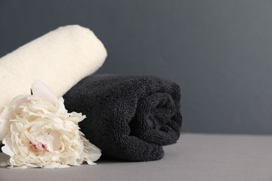 Photo of Soft towels and peony flower on grey background, closeup. Space for text