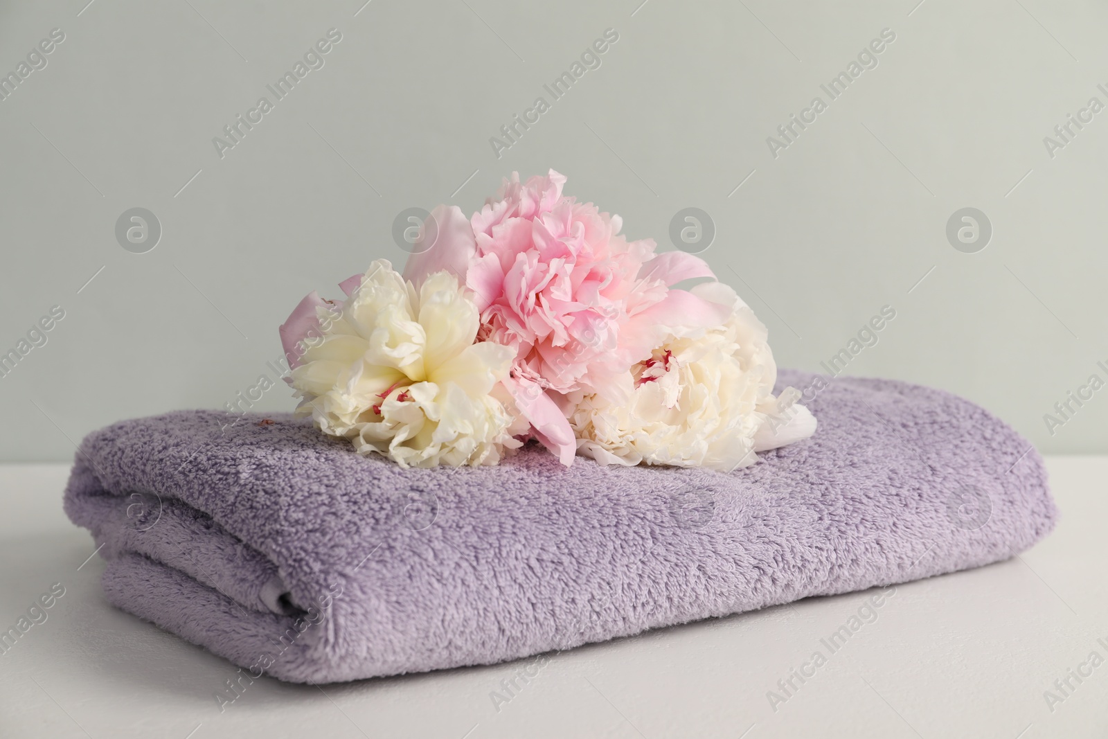 Soft towel and peony flowers on light grey background, closeup Photo of Soft towel and peony flowers on light grey background, closeup