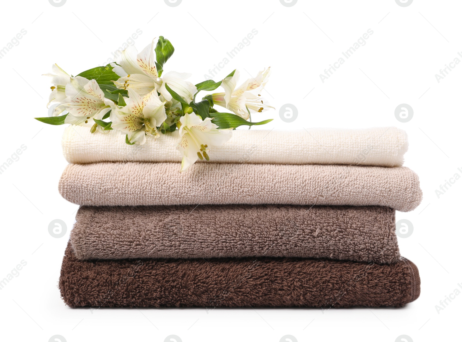 Stack of soft towels and lilies isolated on white Photo of Stack of soft towels and lilies isolated on white