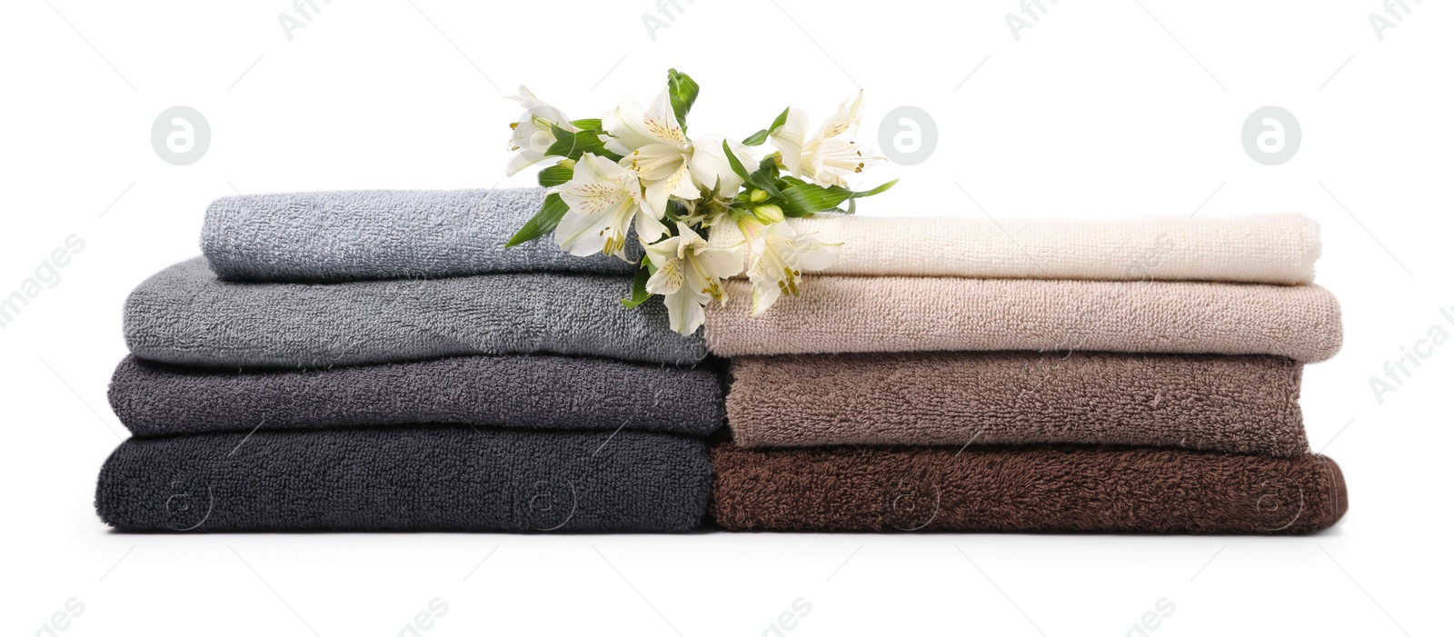 Stack of soft towels and lilies isolated on white Photo of Stack of soft towels and lilies isolated on white