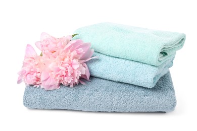 Photo of Stack of soft towels and peony flowers isolated on white