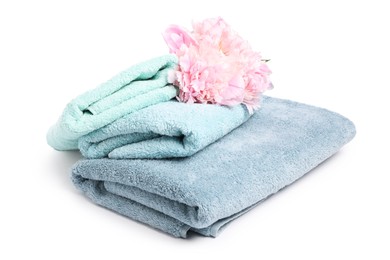 Photo of Stack of soft towels and peony flowers isolated on white