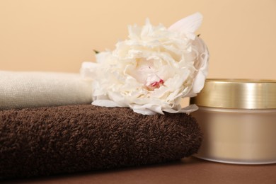 Photo of Soft towels, cosmetic product and peony flower on color background, closeup