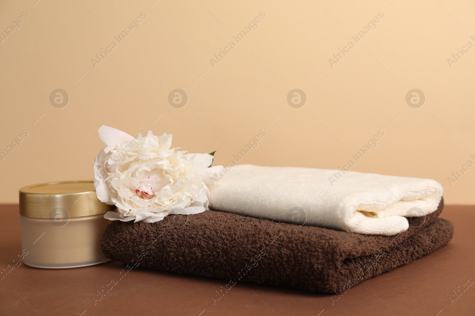 Soft towels, cosmetic product and peony flower on color background, closeup Photo of Soft towels, cosmetic product and peony flower on color background, closeup