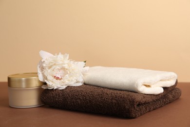 Photo of Soft towels, cosmetic product and peony flower on color background, closeup
