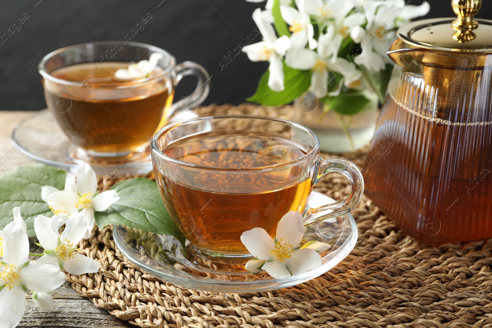 Aromatic jasmine tea in glass cups, flowers and teapot on table, closeup Photo of Aromatic jasmine tea in glass cups, flowers and teapot on table, closeup