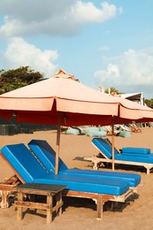 Photo of Sun loungers, beach umbrella and wooden table at resort