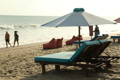 Photo of Bali, Indonesia - May 20, 2025: Sun loungers and beach umbrella at seaside resort