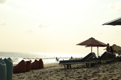 Photo of Bali, Indonesia - May 20, 2025: Sun loungers, beach umbrellas and beanbags at seaside resort