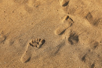 Photo of Footprints on sand as background, top view