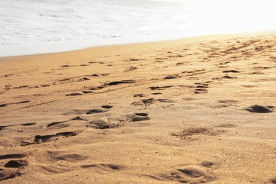 Photo of Sandy beach with footprints near sea, closeup