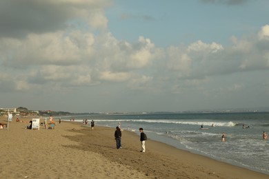 Photo of Bali, Indonesia - May 20, 2025: People walking along seashore and swimming in sea