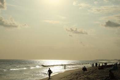 Photo of People relaxing on sandy beach by sea
