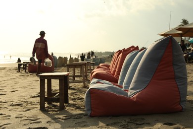 Photo of Bali, Indonesia - May 20, 2025: Beanbags and wooden tables on beach