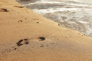 Photo of Footprint on sandy beach near sea, closeup