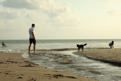 Photo of Bali, Indonesia - May 20, 2025: People and dog spending time on beach