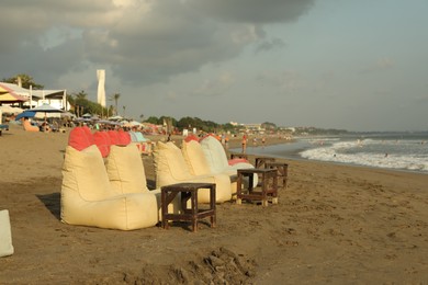 Photo of Bali, Indonesia - May 20, 2025: Beanbags and wooden tables on beach by sea