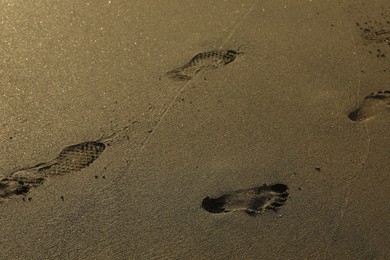 Photo of Many footprints on sand as background, closeup