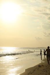 Photo of Bali, Indonesia - May 20, 2025: People walking along seashore at sunrise