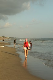 Photo of Bali, Indonesia - May 20, 2025: People walking along seashore and swimming in sea
