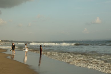 Photo of Bali, Indonesia - May 20, 2025: People walking along seashore and swimming in sea