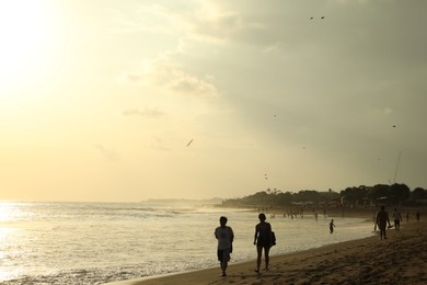 Photo of Bali, Indonesia - May 20, 2025: People walking along seashore at sunrise