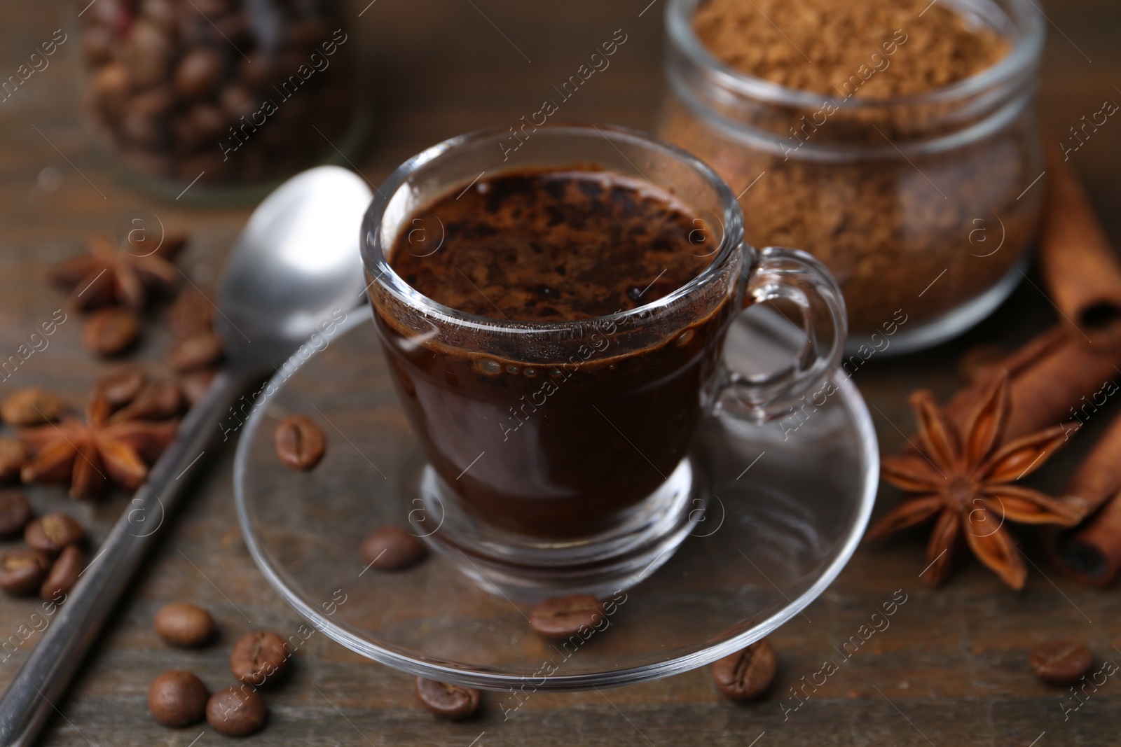 Cup of aromatic coffee, beans, instant powder and spices on wooden table, closeup Photo of Cup of aromatic coffee, beans, instant powder and spices on wooden table, closeup