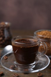 Photo of Cup of aromatic coffee, beans, instant powder and spices on wooden table, closeup