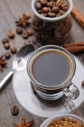 Photo of Cup of aromatic coffee, beans, instant powder and spices on wooden table, closeup
