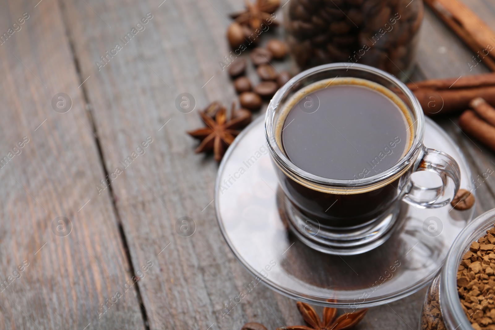 Cup of aromatic coffee, beans, instant powder and spices on wooden table, closeup. Space for text Photo of Cup of aromatic coffee, beans, instant powder and spices on wooden table, closeup. Space for text