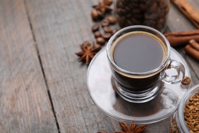Photo of Cup of aromatic coffee, beans, instant powder and spices on wooden table, closeup. Space for text
