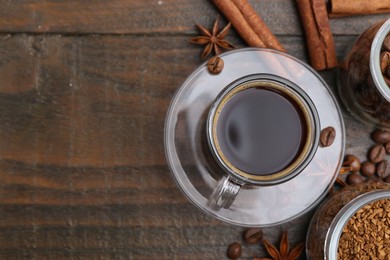 Photo of Cup of aromatic coffee, beans, instant powder and spices on wooden table, flat lay. Space for text
