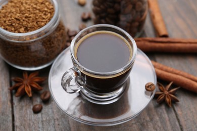 Photo of Cup of aromatic coffee, beans, instant powder and spices on wooden table, closeup