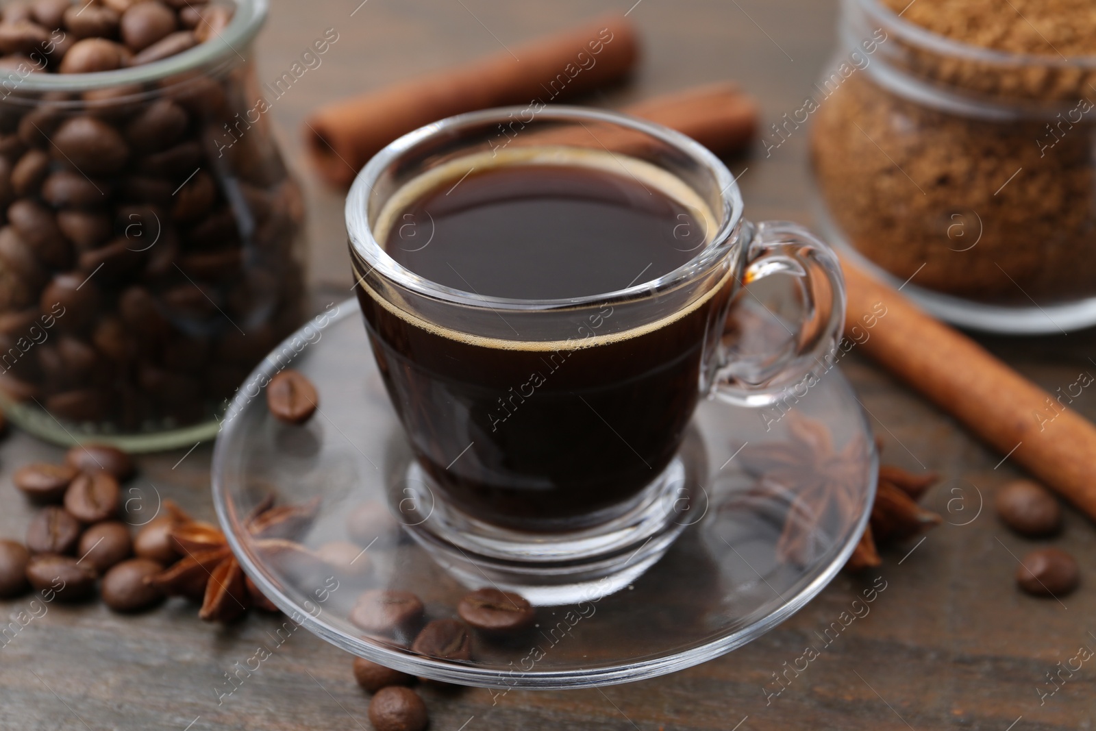 Cup of aromatic coffee, beans, instant powder and spices on wooden table, closeup Photo of Cup of aromatic coffee, beans, instant powder and spices on wooden table, closeup