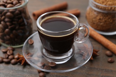 Photo of Cup of aromatic coffee, beans, instant powder and spices on wooden table, closeup