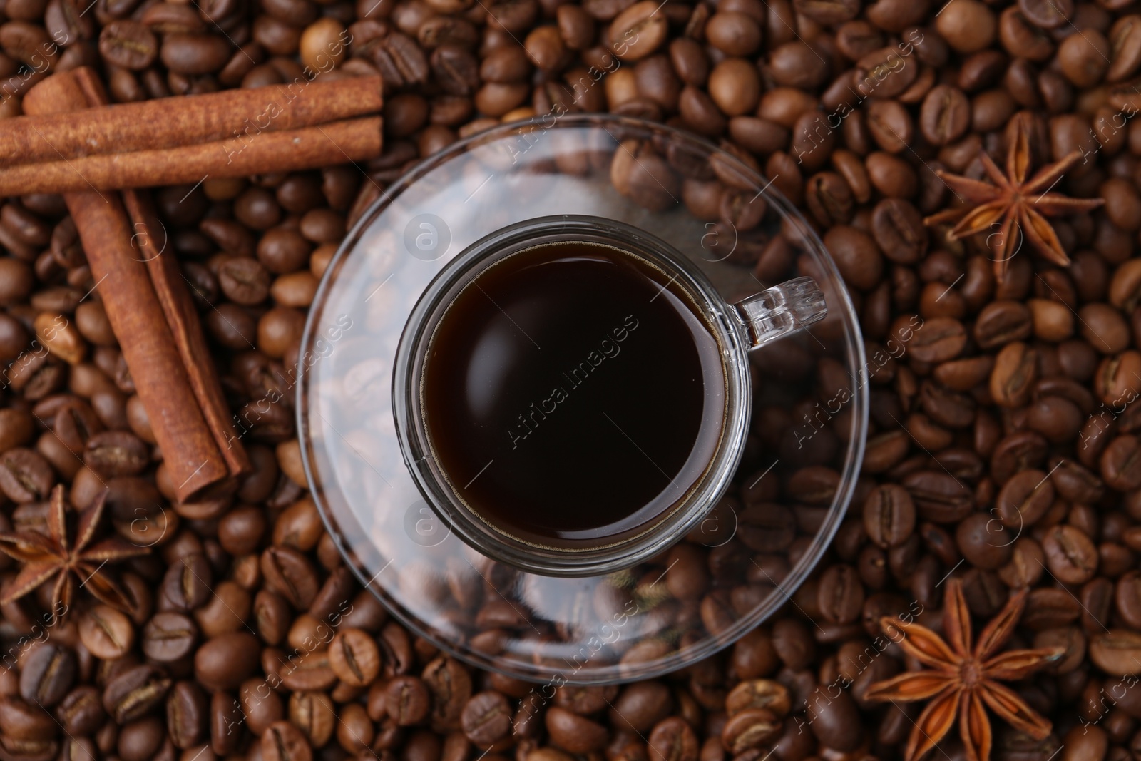 Cup with aromatic coffee, star anise and cinnamon on beans, top view Photo of Cup with aromatic coffee, star anise and cinnamon on beans, top view