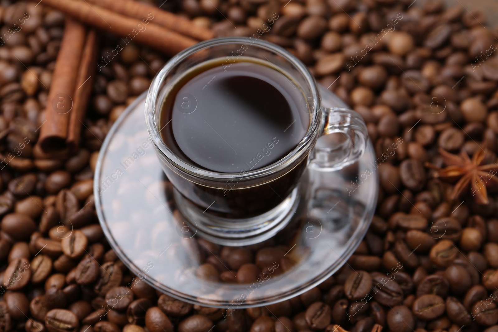 Cup with aromatic coffee, star anise and cinnamon on beans, closeup Photo of Cup with aromatic coffee, star anise and cinnamon on beans, closeup