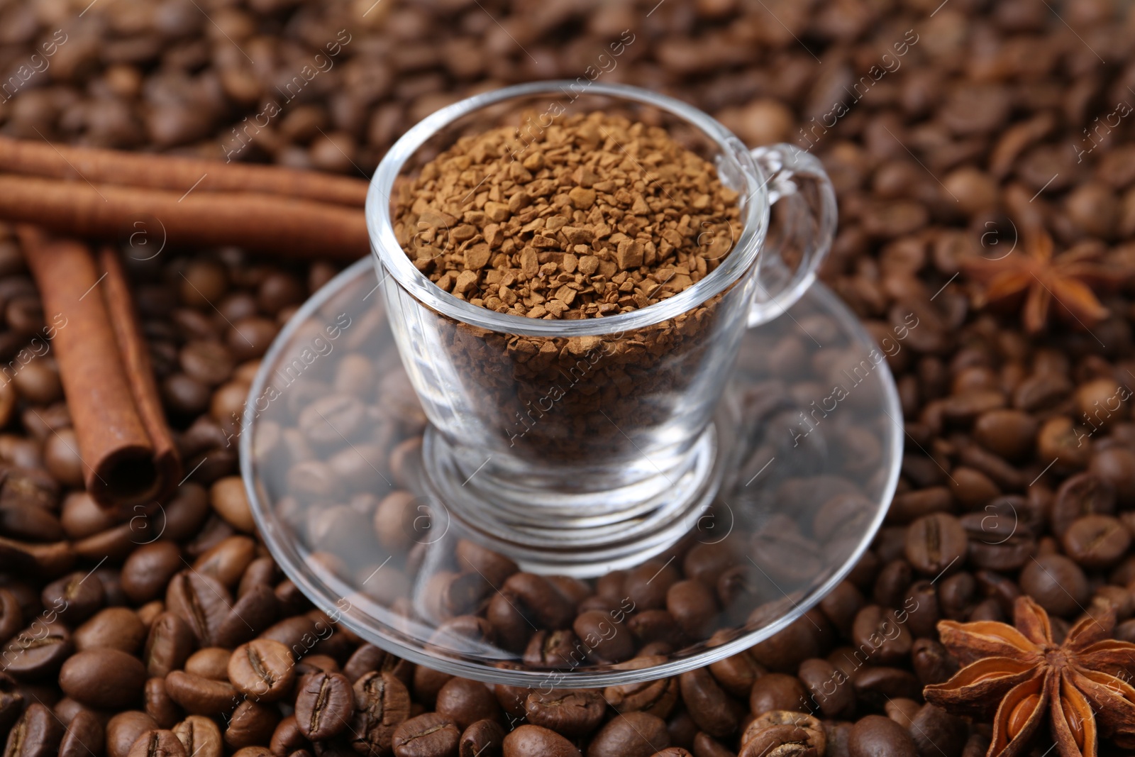 Cup with granulated instant coffee, star anise and cinnamon on beans, closeup Photo of Cup with granulated instant coffee, star anise and cinnamon on beans, closeup