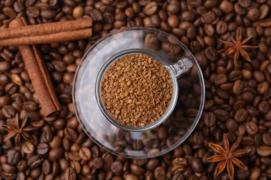Photo of Cup with granulated instant coffee, star anise and cinnamon on beans, top view