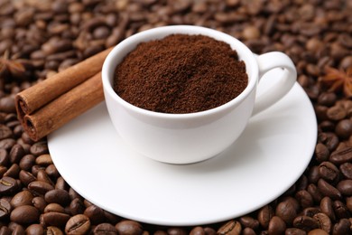 Photo of Cup with instant coffee powder and cinnamon on beans, closeup