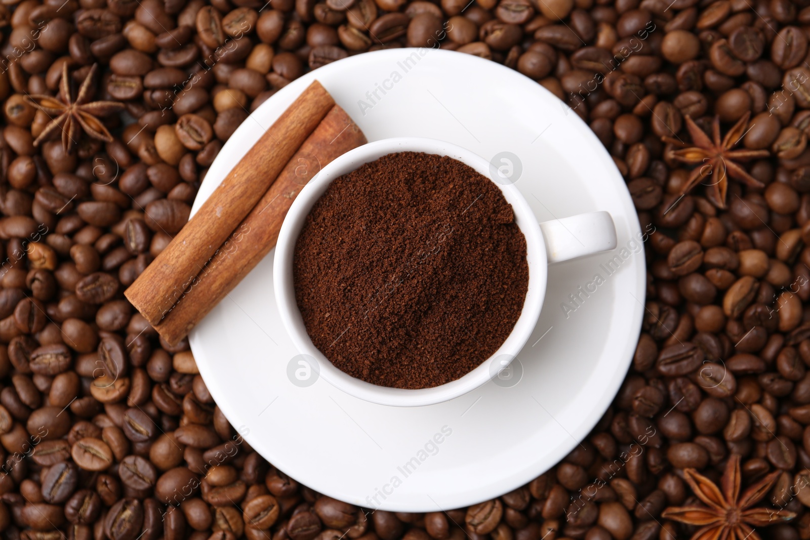 Cup with instant coffee powder and cinnamon on beans, top view Photo of Cup with instant coffee powder and cinnamon on beans, top view