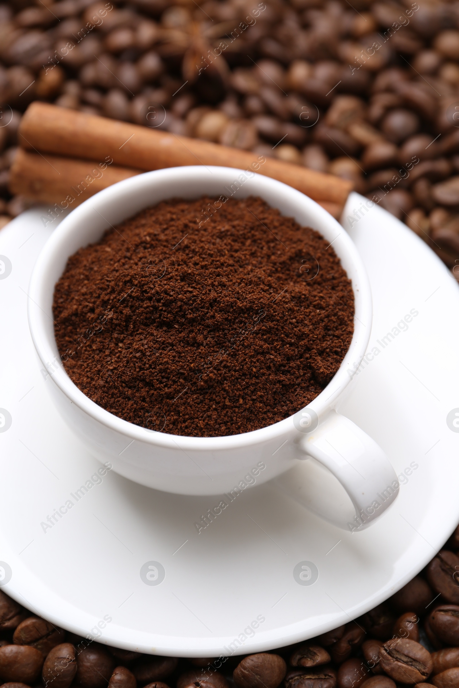 Cup with instant coffee powder and cinnamon on beans, closeup Photo of Cup with instant coffee powder and cinnamon on beans, closeup