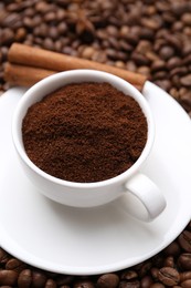 Photo of Cup with instant coffee powder and cinnamon on beans, closeup