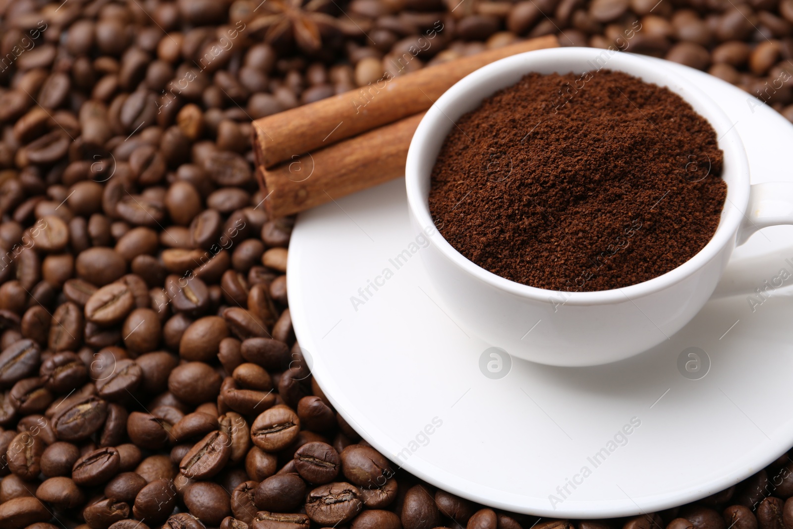 Cup with instant coffee powder and cinnamon on beans, closeup. Space for text Photo of Cup with instant coffee powder and cinnamon on beans, closeup. Space for text