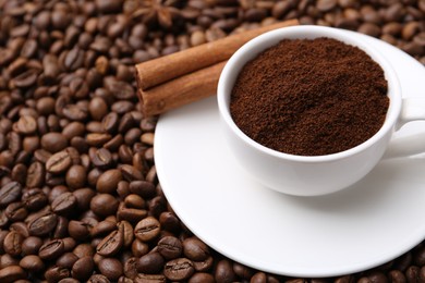 Photo of Cup with instant coffee powder and cinnamon on beans, closeup. Space for text