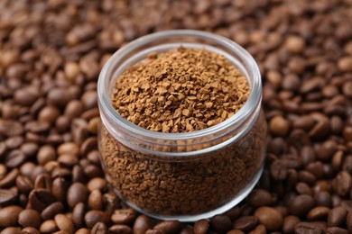 Photo of Glass jar with granulated instant coffee on beans, closeup
