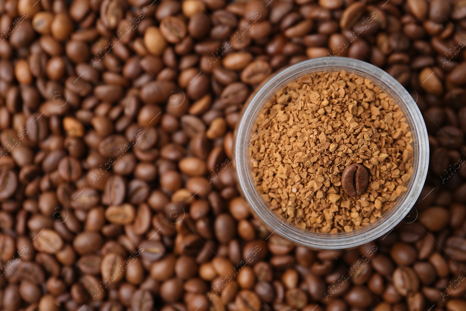 Glass jar with granulated instant coffee on beans, top view. Space for text Photo of Glass jar with granulated instant coffee on beans, top view. Space for text