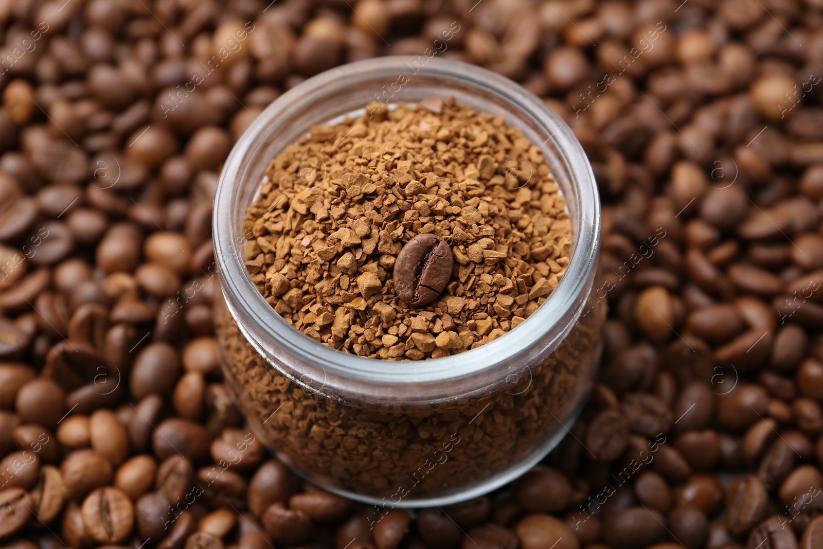 Glass jar with granulated instant coffee on beans, closeup Photo of Glass jar with granulated instant coffee on beans, closeup