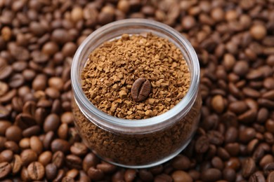 Photo of Glass jar with granulated instant coffee on beans, closeup