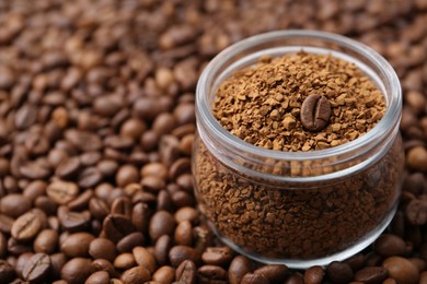 Photo of Glass jar with granulated instant coffee on beans, closeup. Space for text